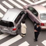 image - overhead shot of two cars collided at intersection, drivers standing around.