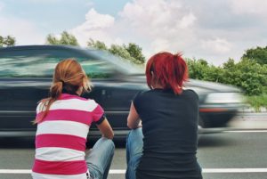 image of two girls sitting stranded at side or road.