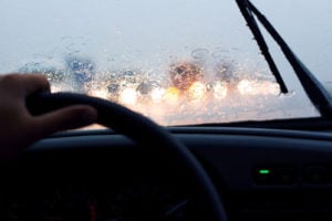 Car with a wet rainy windshield and windshield wiper going