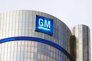 Photo of the outside of a GM building with mirrored titles and a blue sign