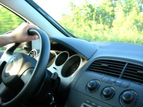 image of someone driving their car with their hand on the steering wheel