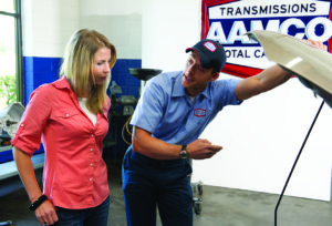 image of aamco mechanic showing customer things about her car engine under hood, hood up.