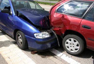 image of car wreck - two cars in a collision, one blue car crashed into rear end of red car.