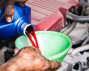 Hand pouring transmission fluid through funnel as for the good car maintenance