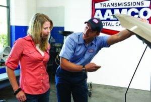 image of woman and aamco mechanic looking under the hood of a car
