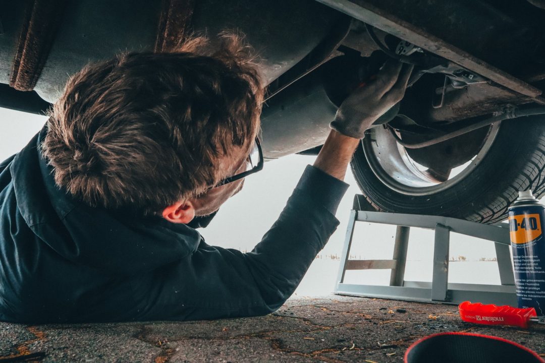 image of mechanic inspecting under carriage of vehicle