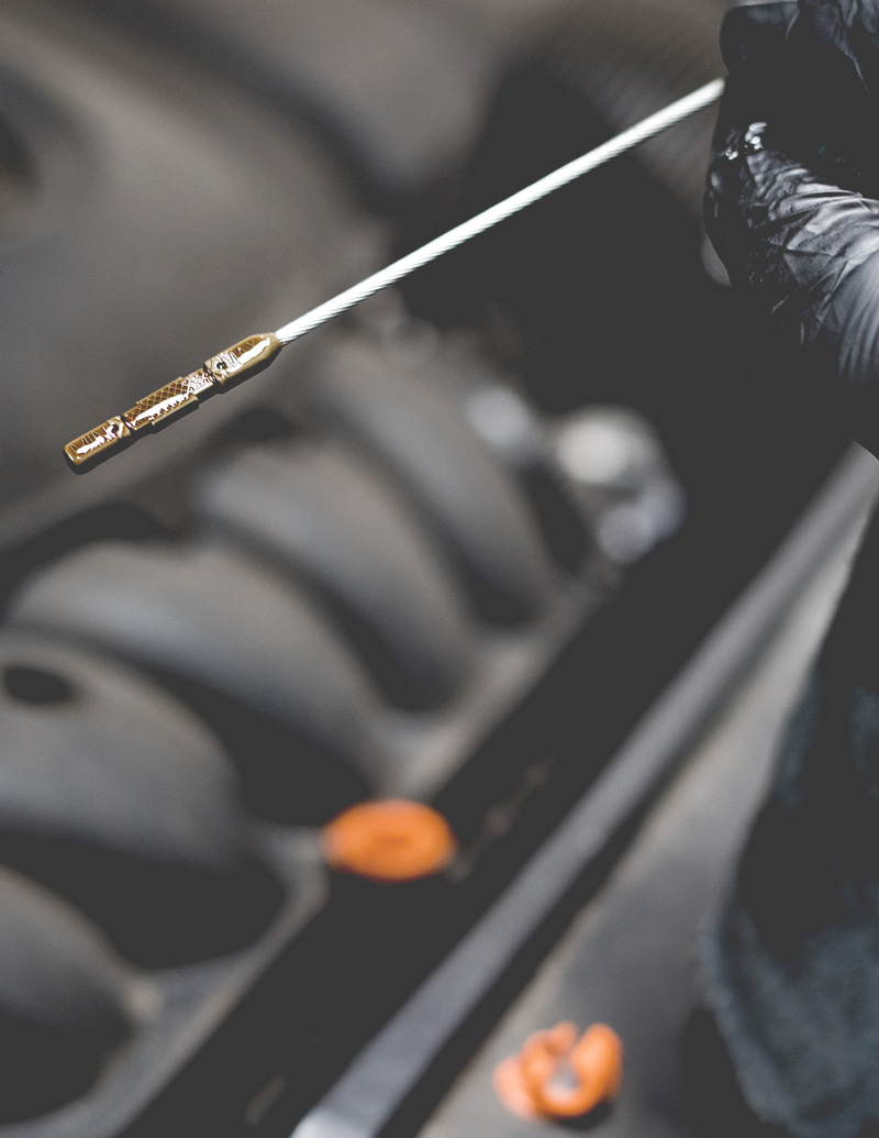 image of mechanic checking engine oil levels on dipstick