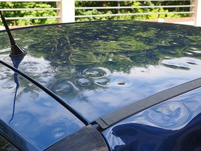 Image of hail damage on the roof of a blue car